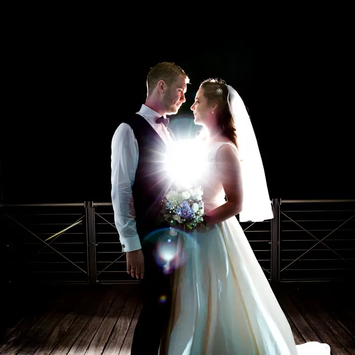 Low-key wedding photography of the wedding couple using studio lights to create a back light effect. Low-Key-Hochzeitsfotografie des Brautpaares unter Verwendung von Studioleuchten zur Erzeugung eines Gegenlichteffekts.