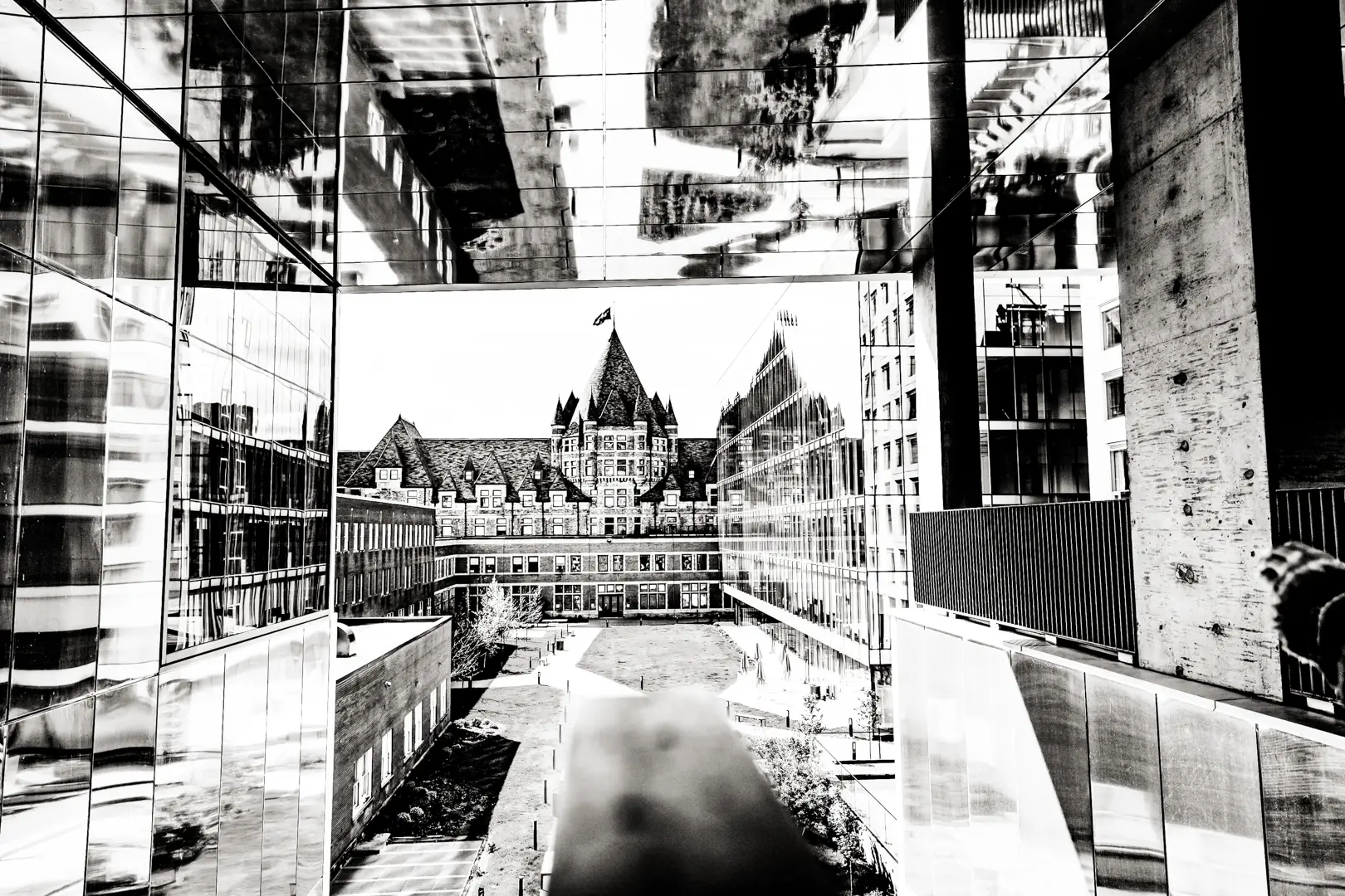 A black and white photo of an old Montreal building framed within a modern building. Ein Schwarz-Weiß-Foto eines alten Gebäudes in Montreal, das innerhalb eines modernen Gebäudes gerahmt ist.